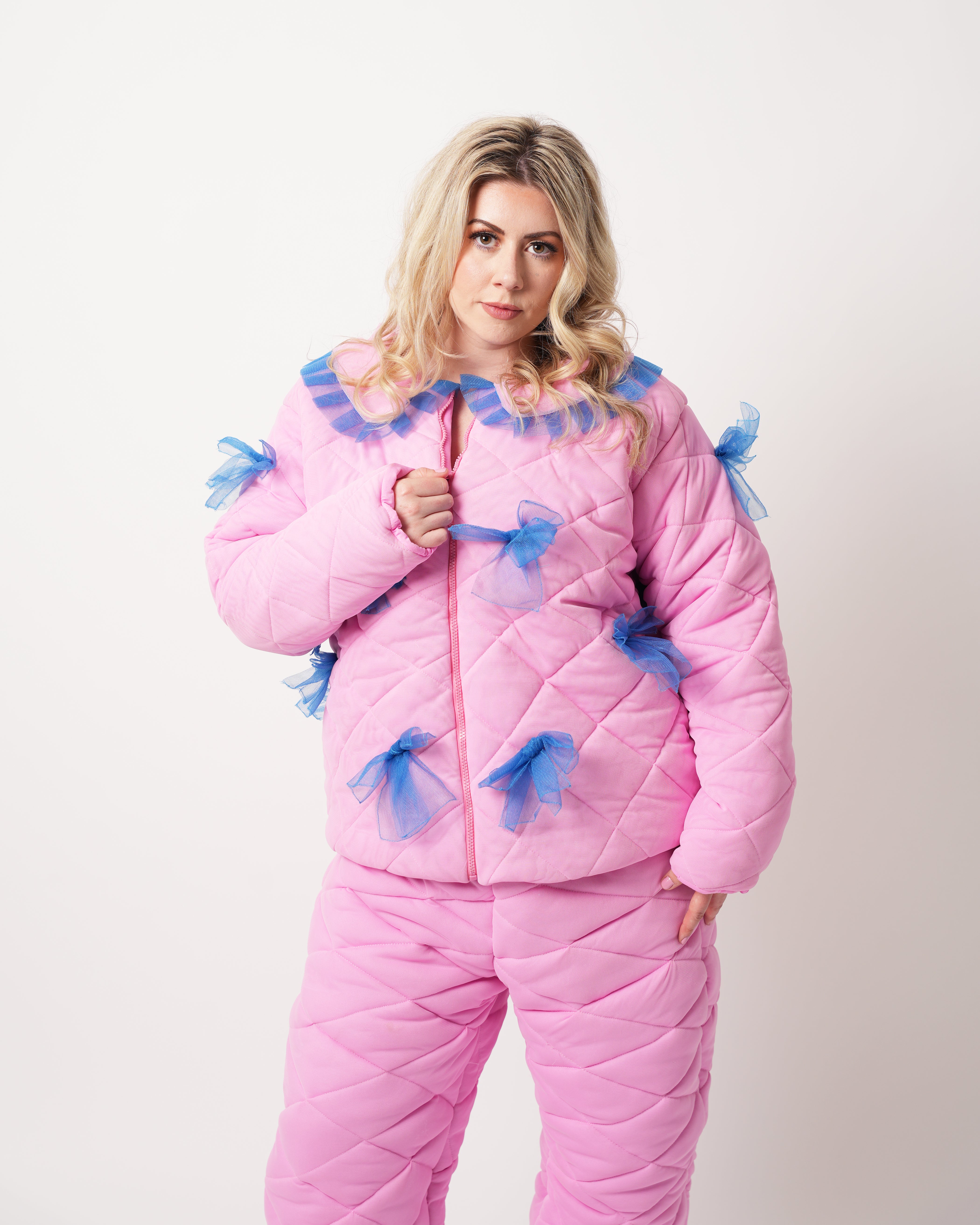 Person wearing a pink quilted winter  outfit with blue accents on a white background